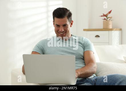 Man using laptop for search on sofa at home Stock Photo