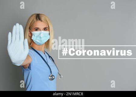 Doctor in protective mask showing stop gesture near hashtag Coronavirus on grey background Stock Photo