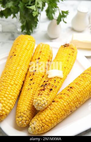 Fresh grilled corn cobs with butter on plate, closeup Stock Photo