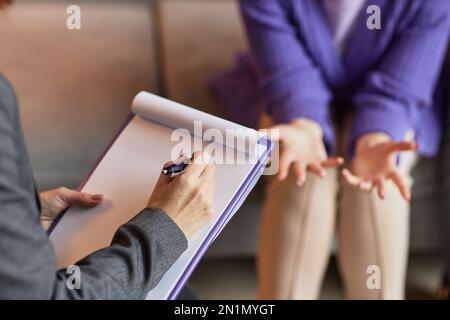 Family psychologist taking notes in document when talking to married couple Stock Photo