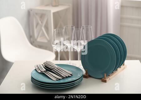 Set of clean dishes, cutlery and wineglasses on white table indoors Stock Photo