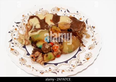 Chocolate mixture with biscuit and different types of chocolate pieces and cream with fresh pineapple ananas and bananas pieces on top on a dough bake Stock Photo