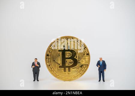 Business , Money, Technology and  cryptocurrency Concept. Two businessman miniature figure people standing with gold bitcoin coins on white background Stock Photo