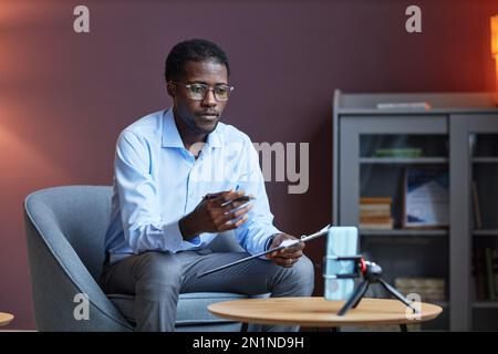 Psychologist having online session with client, he is asking questions and taking notes in document Stock Photo