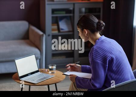 Psychologist having online session with client and writing down important information Stock Photo