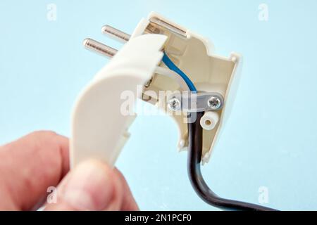 Disassembled European standard electric plug and an electrical cord connected to it. Stock Photo