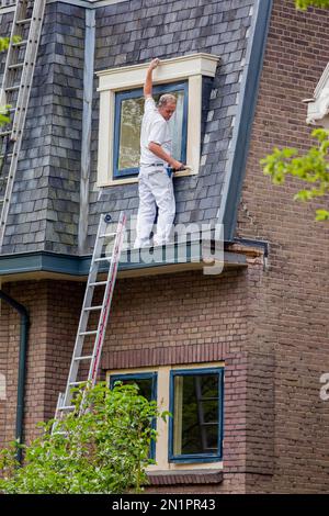 Netherlands, Arnhem A house painter is risking his life while working without any fall protection. Stock Photo