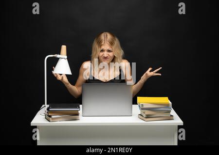 Young nervous business woman is angry on her colleague he is late with sending her an email. Frustrated businessperson in the office on laptop waiting Stock Photo