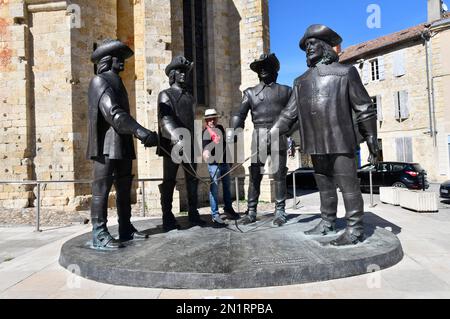 Tourist posing with Statue of d'Artagnan and The Three Musketeers  at Condom, Gers, Gascony, Midi-Pyrenees, France Condom in the Lot-et-Garonne depart Stock Photo