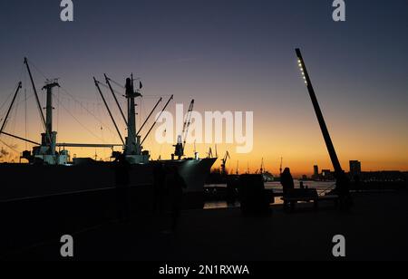 Hamburg, Germany. 06th Feb, 2023. Passers-by walk along the Jan Fedder promenade in the harbor in the evening sun. Credit: Marcus Brandt/dpa/Alamy Live News Stock Photo