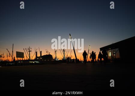 Hamburg, Germany. 06th Feb, 2023. Passers-by walk along the Jan Fedder promenade in the harbor in the evening sun. Credit: Marcus Brandt/dpa/Alamy Live News Stock Photo