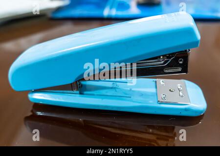 Close up side view of light blue stapler isolated on glass background Stock Photo