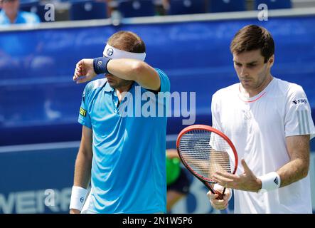 Gilles Muller, of Luxembourg, left, wipes away sweat in between