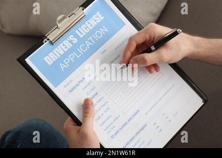 Man filling in driver's license application form, closeup Stock Photo