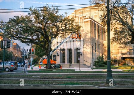 NEW ORLEANS, LA, USA - JANUARY 31, 2023: Front of Temple Sinai synagogue, a repair worker on a lift and a man waiting for a street car on St. Charles Stock Photo