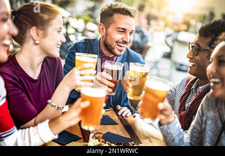 Young people drinking beer pints at brewery bar garden - Genuine beverage life style concept with guys and girls sharing happy hour together Stock Photo