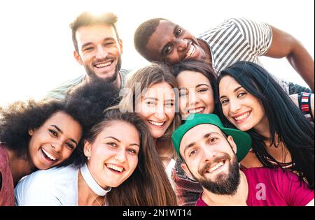 Multicultural guys and girls taking funny selfie - Happy millenial friendship and life style concept on young multiracial best friends having fun day Stock Photo