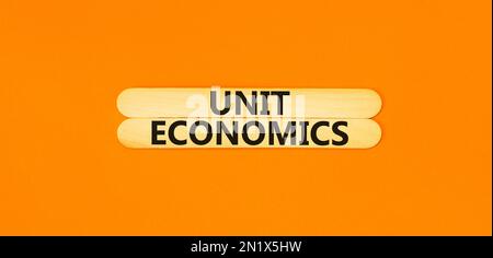 Unit economics symbol. Concept words Unit economics on wooden stick. Beautiful orange table orange background. Business and unit economics concept. Co Stock Photo