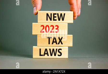 New 2023 tax laws symbol. Concept words New 2023 tax laws on wooden blocks. Beautiful grey table grey background. Businessman hand. Business new 2023 Stock Photo