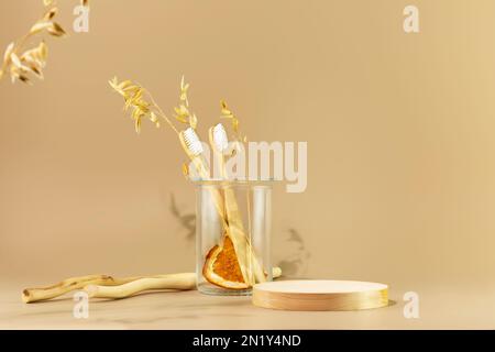 Empty podium for montage of organic oral care products. Eco friendly still life with wooden stage, toothbrushes in glass jar on beige background. Scen Stock Photo