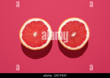 Top view with two slices of grapefruit isolated on a magenta colored background. Grapefruit sliced in half minimalist on a vibrant table Stock Photo