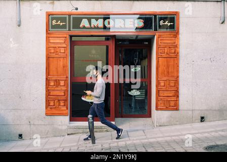 Madrid, Spain - October 10, 2020: Asian man walking down the street in front of a traditional restaurant in the trendy neighborhood of Lavapies. Stock Photo