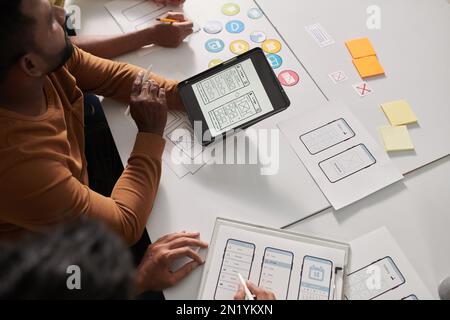 Group of UX designers discussing sketch of mobile application interface design and offering ideas Stock Photo