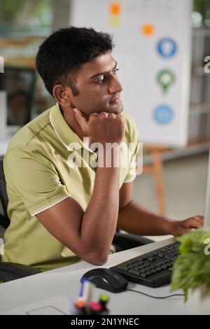 Pensive or bored UX designer working on interface of new mobile application Stock Photo