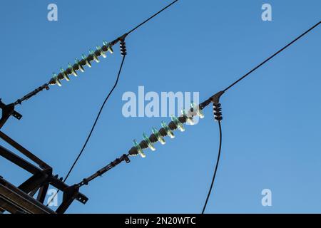 High voltage electric transmission line with glass insulators close-up on blue sky background Stock Photo