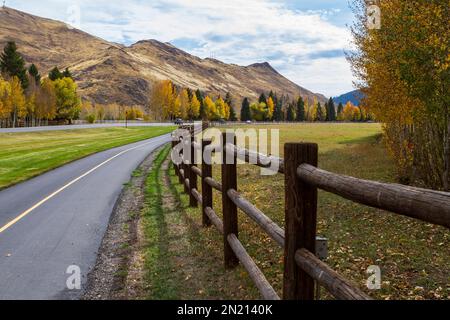 A paved bike path parallels the road into town in Sun Valley, Idaho, USA, on a autumn day with lots of yellow foliage on aspens and cottonwood trees. Stock Photo