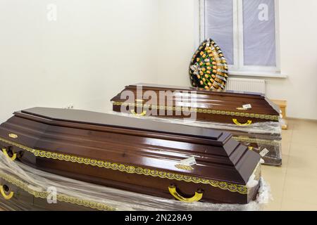 Interior of room with funeral accessories. Shop selling coffins, funeral wreaths and flowers. Stock Photo