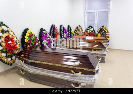 Interior of room with funeral accessories. Shop selling coffins, funeral wreaths and flowers. Stock Photo