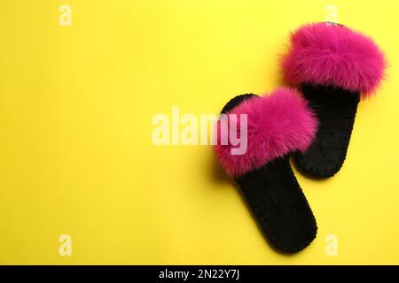 Pair of soft slippers on yellow background, flat lay. Space for text Stock Photo