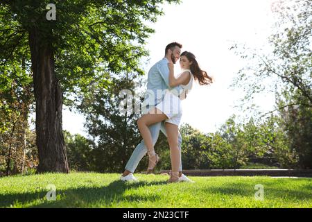 Lovely young couple dancing together in park on sunny day Stock Photo