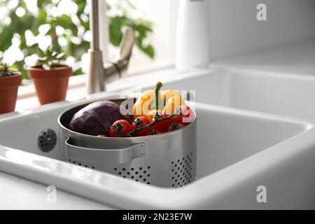 Colander pot with fresh vegetables in kitchen sink Stock Photo