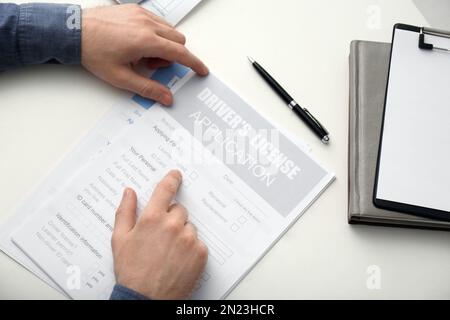 Man with driver's license application form at white table, above view Stock Photo
