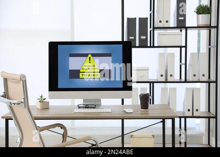 Computer with warning about virus attack on screen in office Stock Photo