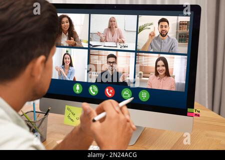 Man having video chat with colleagues at table in office, closeup. Team work Stock Photo