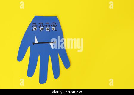 https://l450v.alamy.com/450v/2n24b5w/funny-blue-hand-shaped-monster-on-yellow-background-top-view-with-space-for-text-halloween-decoration-2n24b5w.jpg