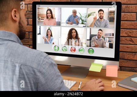 Man having video chat with colleagues at table in office, closeup. Team work Stock Photo