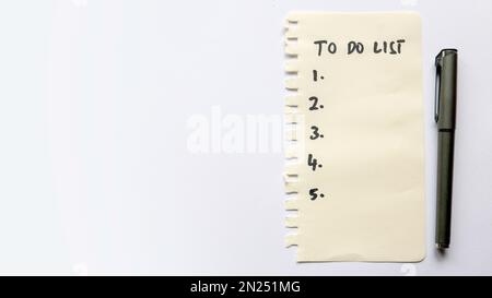 A list of to do list written on a piece of paper with pen on white background with copy space. Stock Photo