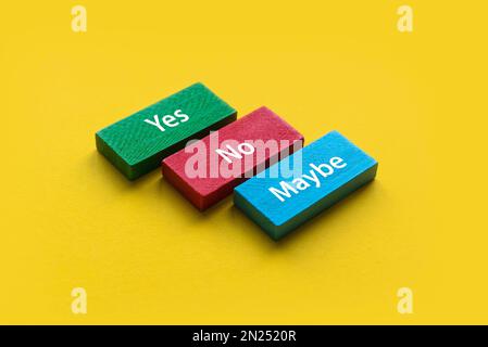 Yes, No and Maybe wooden block on a yellow background. Stock Photo