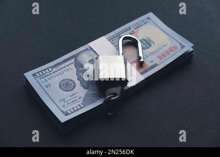 Selective focus of an open padlock with key with money on a black background Stock Photo
