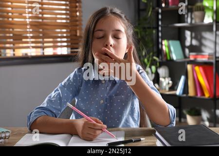 Tired preteen girl at table. Doing homework Stock Photo