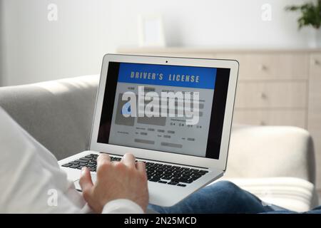 Man using laptop to fill driver's license application form at home, closeup Stock Photo