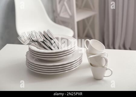 Set of clean dishware and cutlery on white table indoors Stock Photo