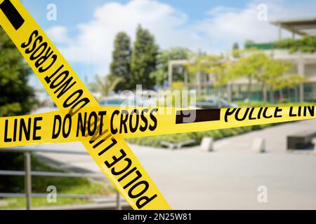 Yellow police tape isolating crime scene. Blurred view of city street Stock Photo