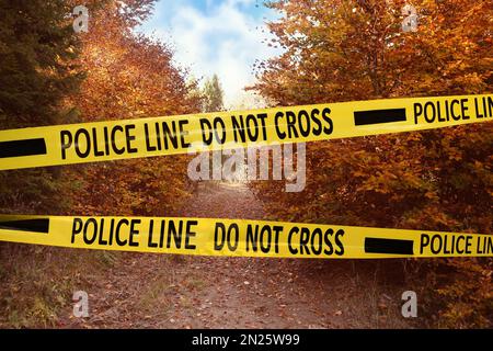 Yellow police tape isolating crime scene. Restricted area of autumn park Stock Photo