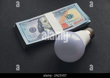 A bulb and money on a black background. Stock Photo