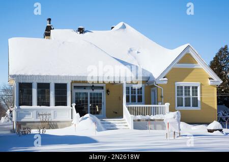 Rear of yellow with white trim country cottage style house in winter. Stock Photo